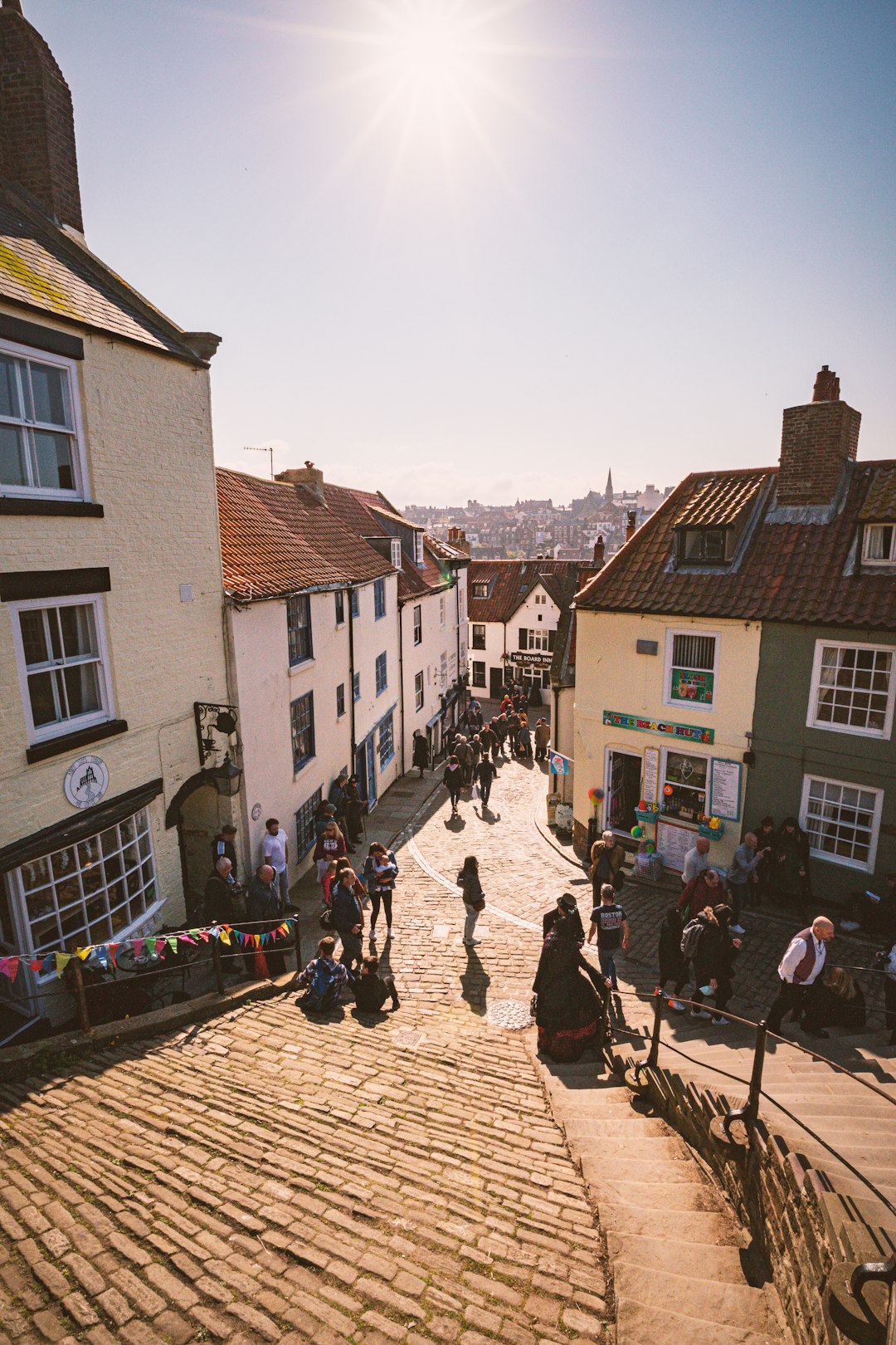 Photo by Marco Angelo a group of people walking on a brick road between buildings